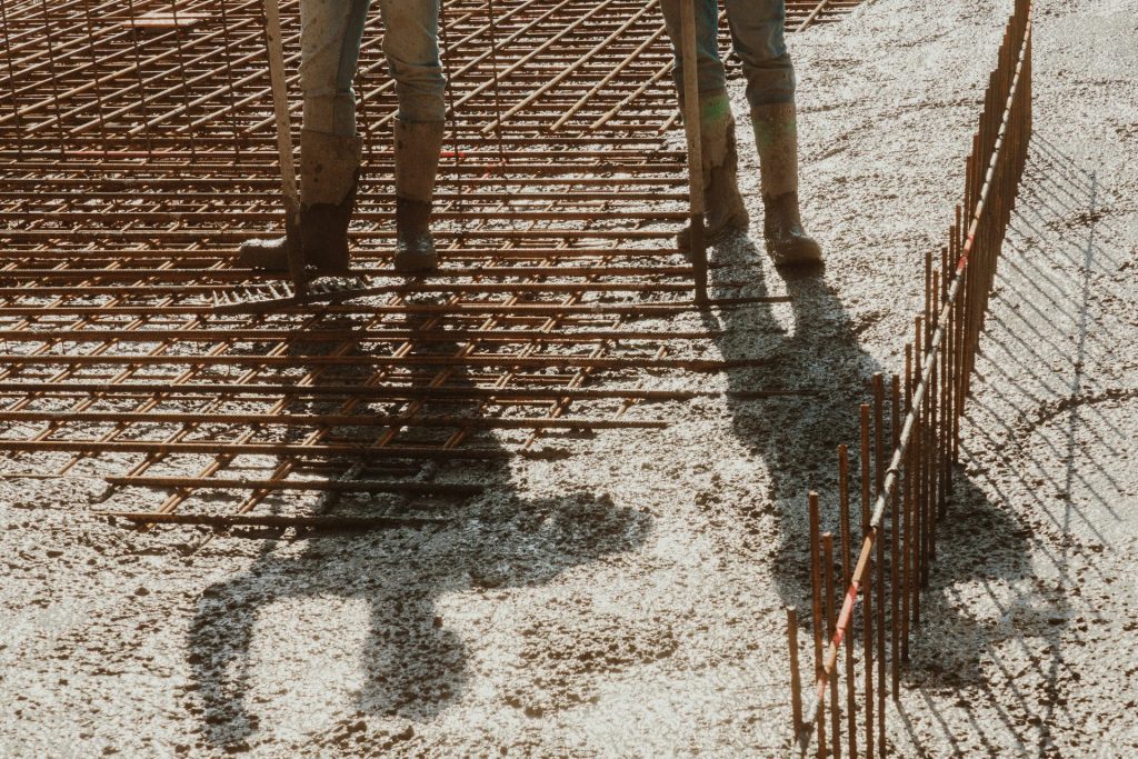 Ein Mann steht neben einem Stapel Metallstangen.